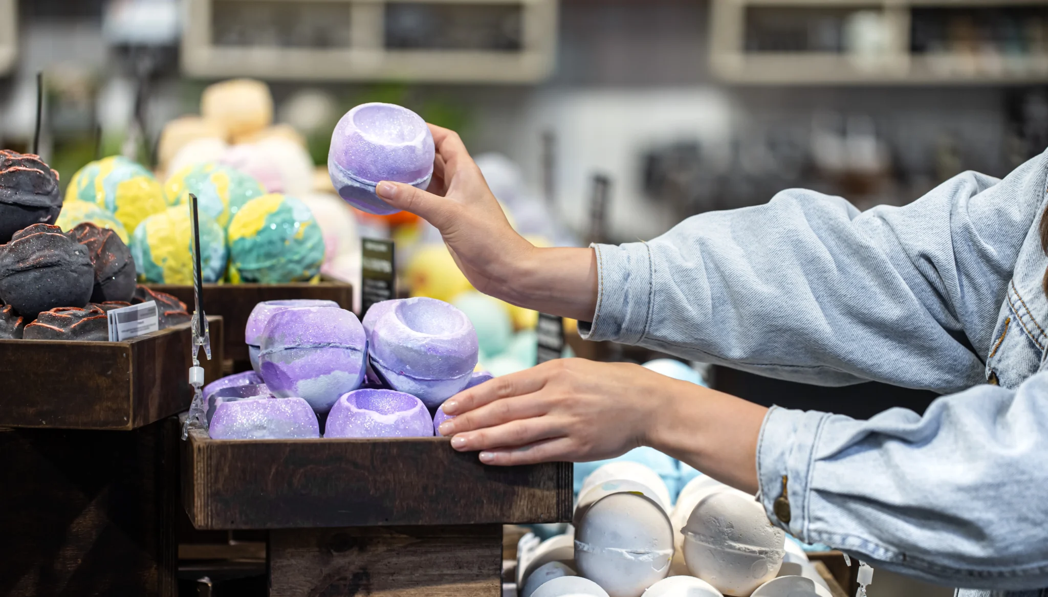 Female hands holding bright colored bath bombs and cosmetic at a small business market