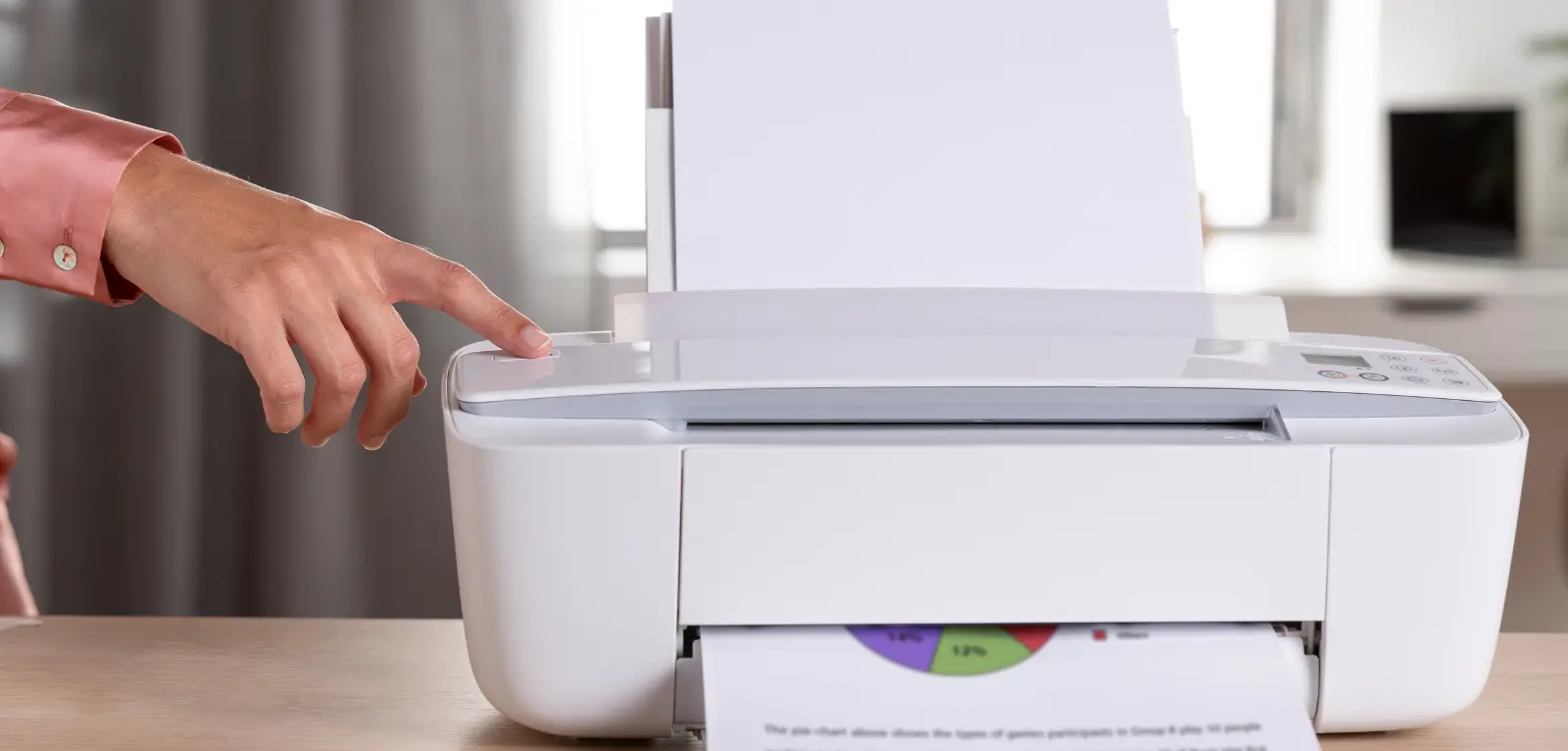 A hand presses a button on a printer that prints a page with a chart